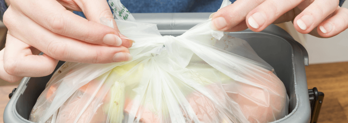 Dwylo'n clymu leinin cadi bwyd mewn cadi bwyd